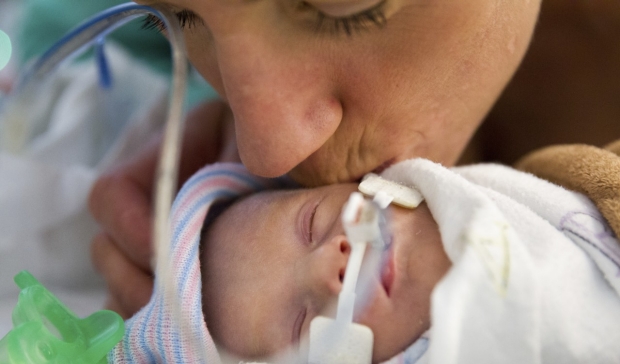 Mom kisses baby in NICU