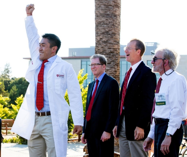 Medical student raising his arm in triumph after receiving his white coat