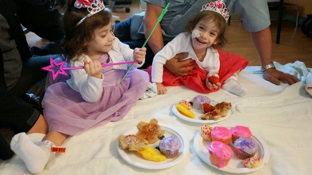 Twin toddlers in princess outfits eating cupcakes and treats