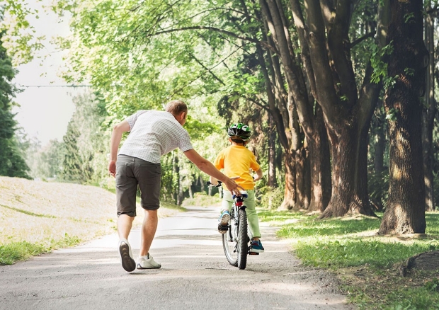 Father helping a child learn to ride a bike