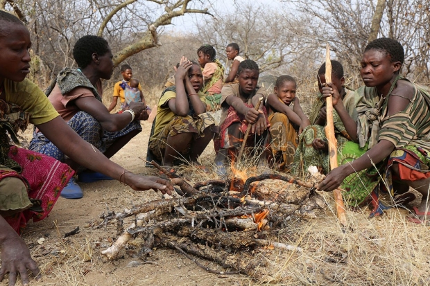 Group of Hadza hunter-gatherers gathered around a fire