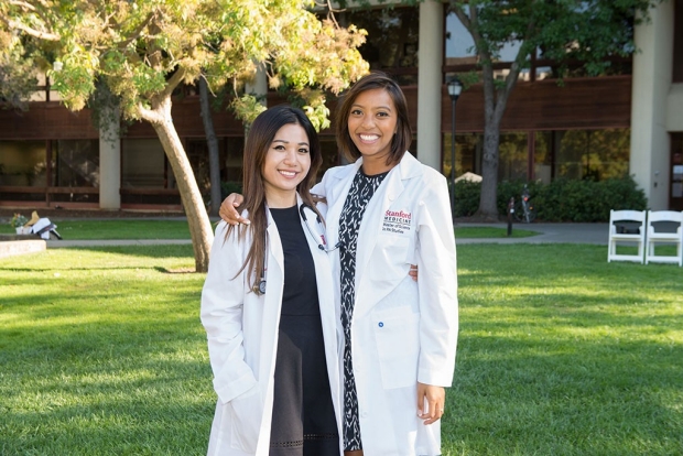Two female students in white coats standing on a lawn