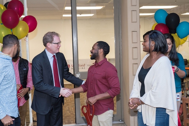 Man shaking hands with another man with balloons in the background