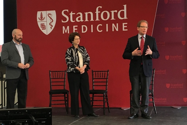 Samuel Zelch, Marcia Cohen and Lloyd Minor stand on a stage