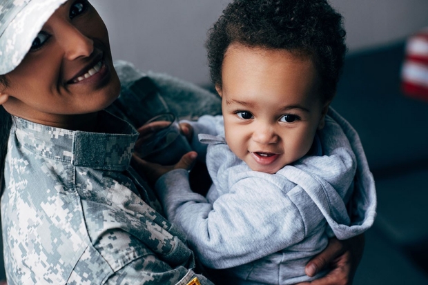 Woman in military fatigues holding a young child